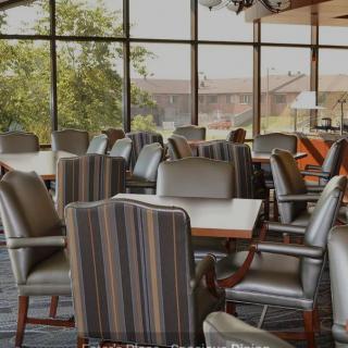 A dining area with multiple chairs and tables near large windows.