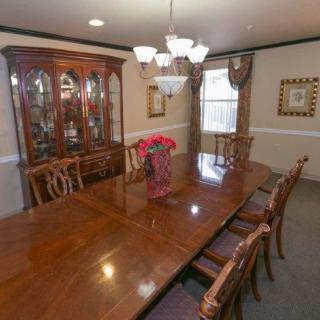 A formal dining room with a large wooden table and matching chairs, complemented by a chandelier and china cabinet.