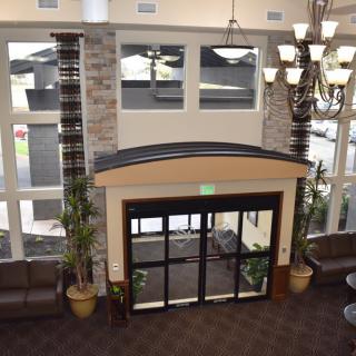 A modern lobby area with large windows, decorative lighting, and plants near the entrance.