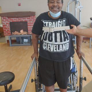 A person participating in physical therapy, using a walker for support and displaying a positive attitude.