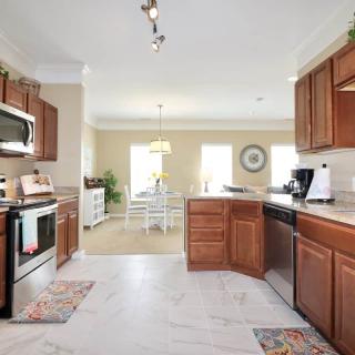 A modern kitchen with wooden cabinets and stainless steel appliances, leading into a bright dining area.