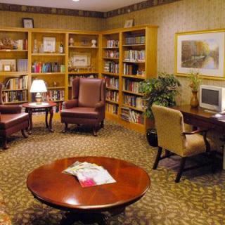 A cozy library reading area with bookshelves, armchairs, and a computer desk.