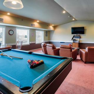 A cozy game room featuring a pool table and comfortable leather chairs facing a television.