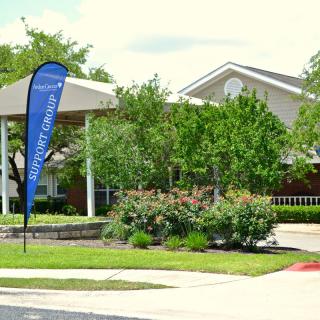A residential building with surrounding greenery and a small driveway.