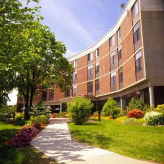 A sunny day view of a modern building surrounded by well-maintained gardens and pathways.
