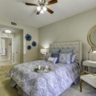 A cozy bedroom with a stylish decor, featuring a bed with patterned bedding, bedside tables, lamps, and decorative wall items.