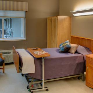 A clean and well-organized hospital room with a bed, chair, and window.