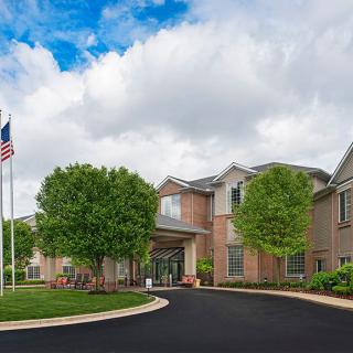 A brick building with a driveway and flagpole under a cloudy sky.