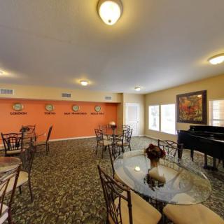A cozy living room with dining tables, a piano, and decorative elements.