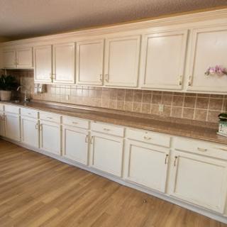 A spacious kitchen featuring cream-colored cabinets and a wooden floor.