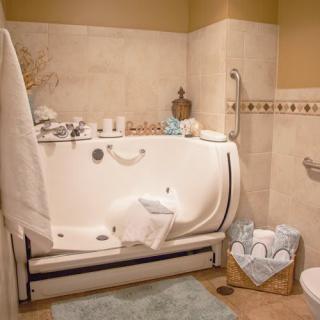 A luxurious bathroom featuring a walk-in bathtub equipped with safety handles, surrounded by elegant decor and neatly arranged towels.
