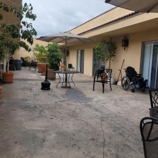 An outdoor patio area with tables, chairs, potted plants, and an umbrella.