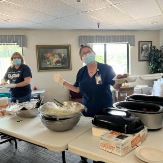 Volunteers wearing masks serve food in a community setting.