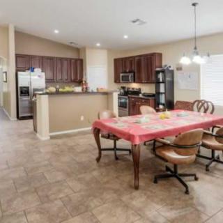 An open-plan kitchen and dining area featuring wooden cabinets, tiled flooring, and modern lighting.