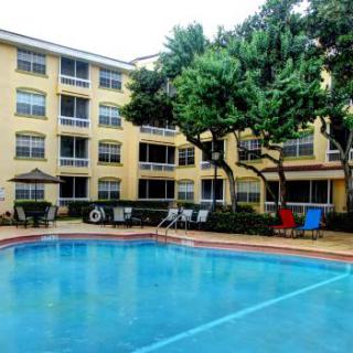 An apartment complex with an outdoor swimming pool surrounded by trees.