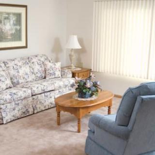 A cozy living room with a floral sofa, wooden coffee table, and blue armchair.