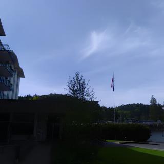 A scenic view of a building beside a flagpole with a blue sky and clouds overhead.