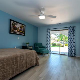 A spacious bedroom with a bed, comfortable chair, and sliding glass doors leading outside.