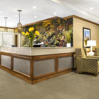 A well-decorated lobby area featuring a reception desk, comfortable seating, and vibrant floral arrangements.