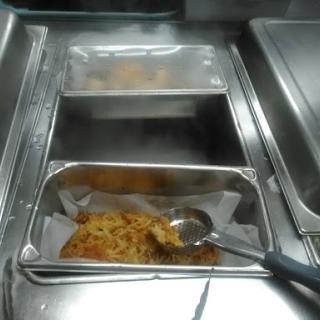 A serving tray in a cafeteria featuring a portion of pasta, ready to be served.