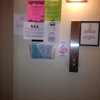 A wall near an elevator covered with various notices and posters.
