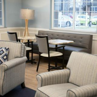 A cozy lounge area with comfortable seating, tables, and a large window.
