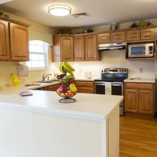 A modern kitchen with wooden cabinets and a center island displaying a fruit bowl.