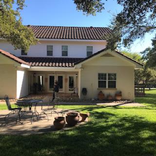A sunny afternoon view of a spacious home with a well-kept backyard.