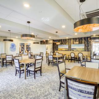A modern dining area with neatly arranged tables and chairs, featuring stylish lighting fixtures and contemporary decor.