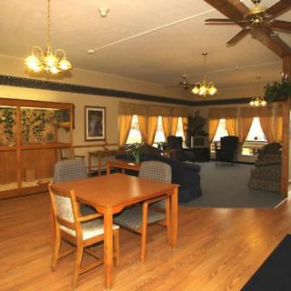 A cozy indoor space featuring a dining and living area with wooden floors, comfortable seating, and warm lighting.