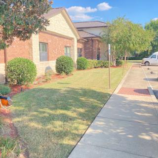 A pleasant outdoor view featuring well-maintained grass, a building, and a clear blue sky.