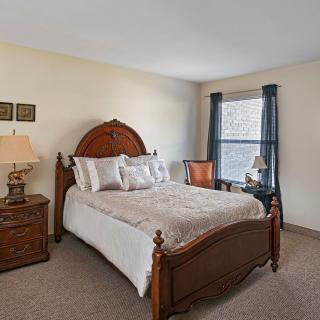 A cozy bedroom with traditional furniture and a large window.