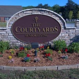 A landscaped stone sign for The Courtyards Senior Living.