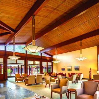 A spacious lobby with a wooden ceiling, modern furniture, and elegant lighting.