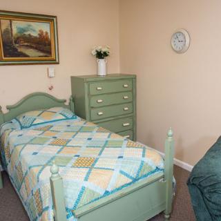 A cozy bedroom with a single bed and dresser, decorated with a painting on the wall.