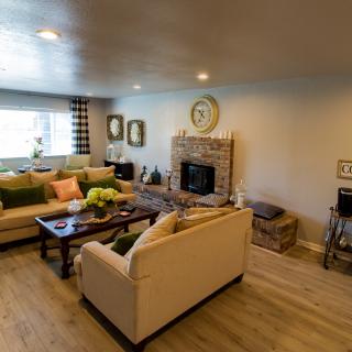 A cozy living room featuring a comfortable sofa set, a central coffee table, and a fireplace, accented with stylish decor and wood flooring.