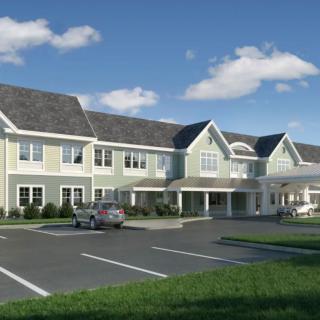 A two-story residential building with an adjacent parking lot and a clear blue sky.
