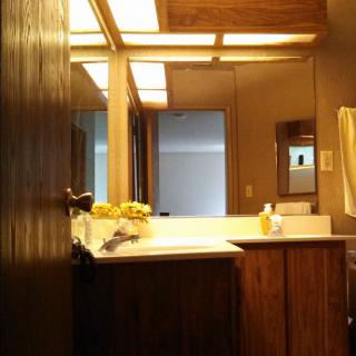 A warm and cozy bathroom with a mirror, sink, and wooden cabinets.