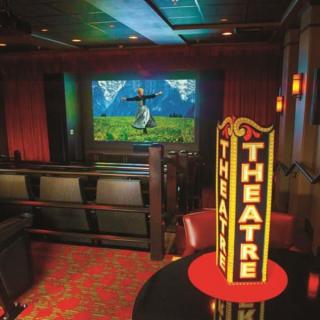 An indoor theater with a screen displaying a movie, featuring cozy seating and classic decor.