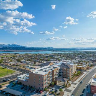 A stunning aerial view showcasing a vibrant city landscape against the backdrop of mountains and a serene body of water.