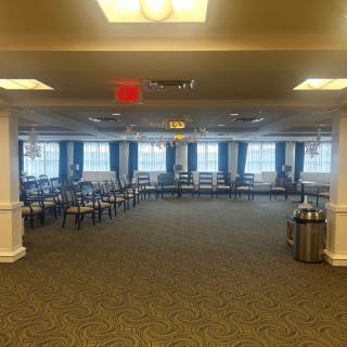 An empty conference room with rows of chairs and large windows.
