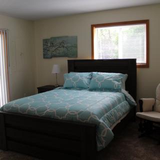 A cozy bedroom with a neatly made bed, a window, and simple decor.