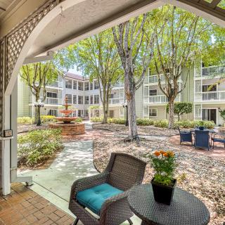A cozy patio overlooking a lush courtyard with trees and a multi-story building in the background.
