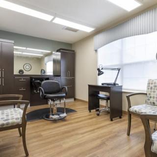 A well-lit salon interior featuring a barber chair, mirror, and seating area.