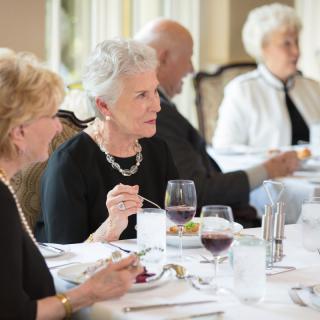 A group of elderly people enjoying a meal together in a formal dining setting.
