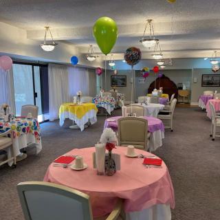 A festive dining area with decorated tables and colorful balloons set for a celebration.