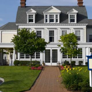 A charming two-story house with a manicured garden and brick pathway.