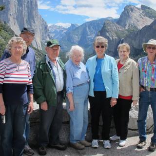 A group of people posing together in front of a mountainous landscape.