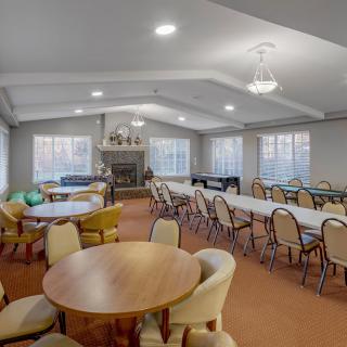 A well-lit conference room with multiple tables and chairs arranged for meetings or gatherings.