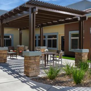 A modern patio with a pergola and outdoor seating area, surrounded by landscaping.